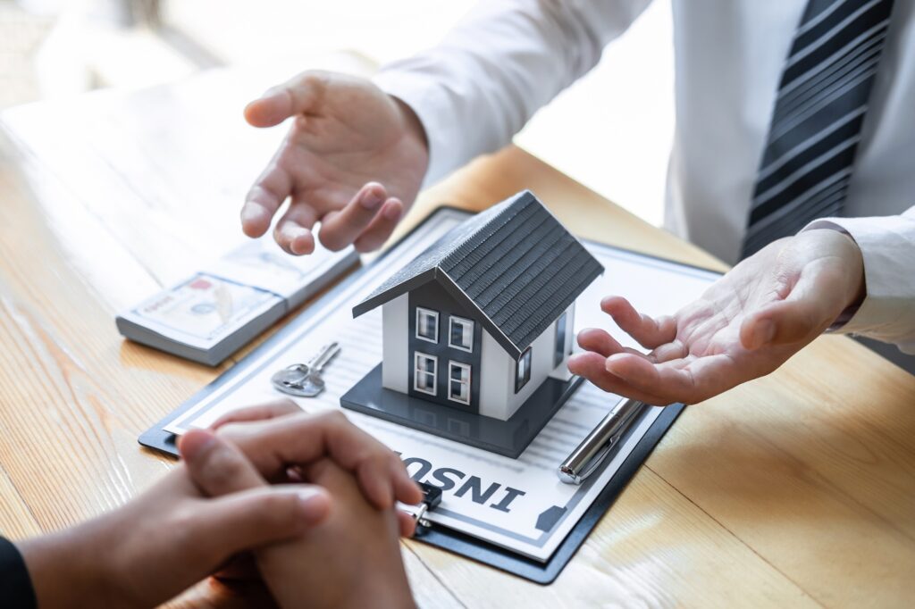 Estate agent are presenting home loan and giving house to client after discussing and signing