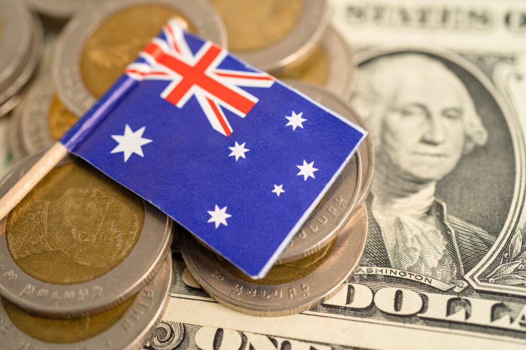 Stack of coins with Australia flag and US dollar banknotes.